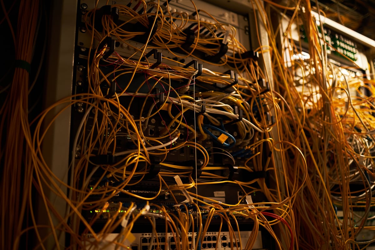 On-premise server rack with tangled cables. IT maintenance burden before cloud move.